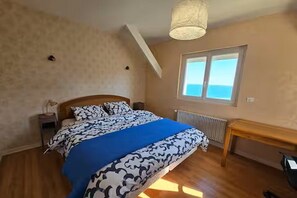 Relax in this serene bedroom with a large bed, sloped ceiling, and a window offering a view of the sky.