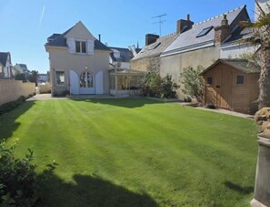 Residential property with a well-maintained lawn and a house with a pitched roof and conservatory.