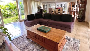 Uma sala de estar espaçosa com sofá modular, mesa de centro de madeira e uma janela grande com vista para o verde.