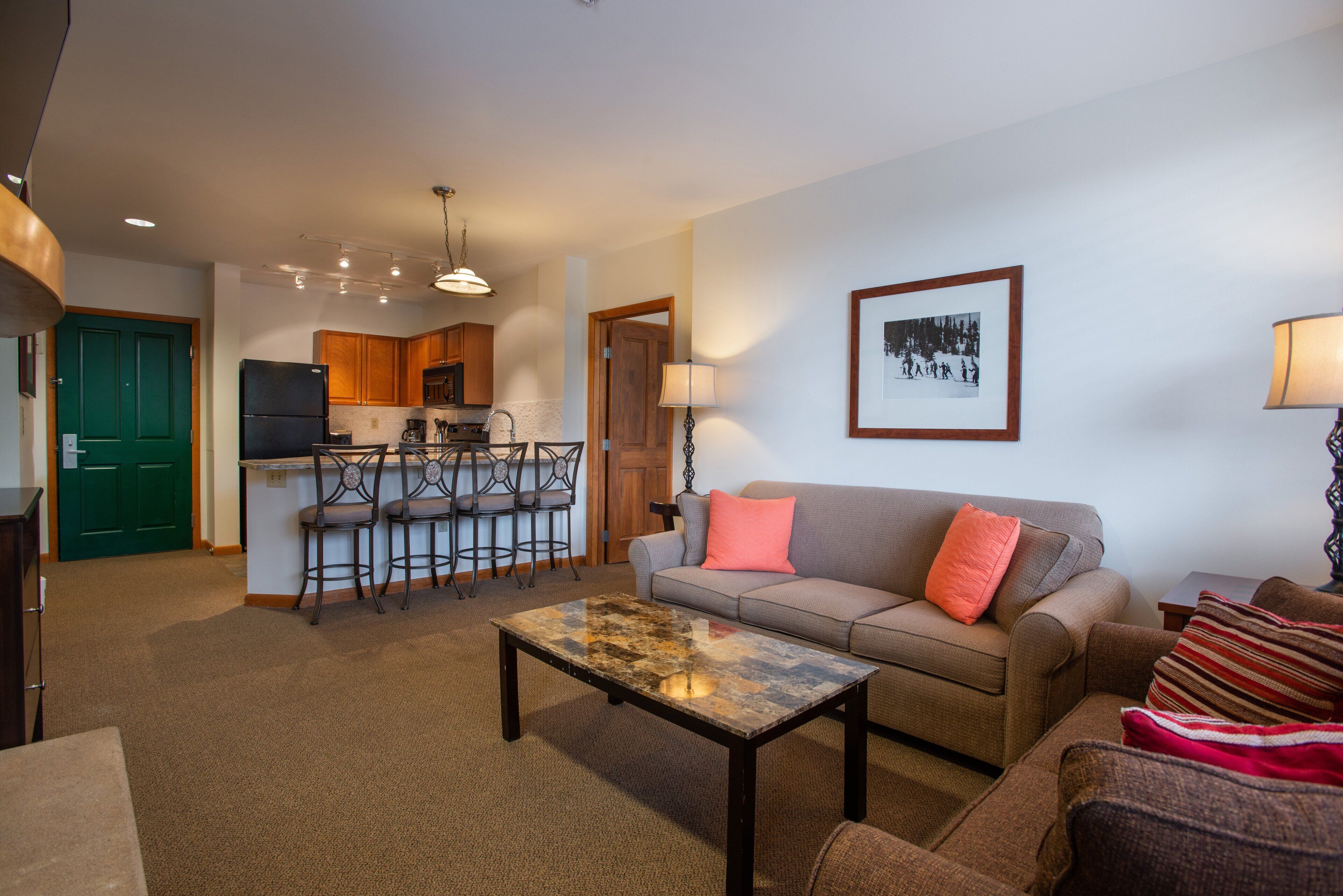 A living room with a sofa, a coffee table, and a kitchen area in the background.