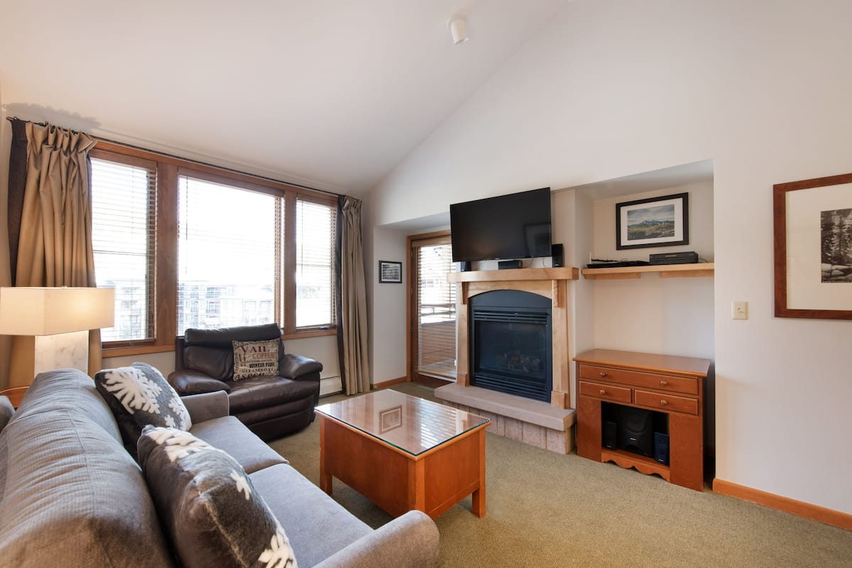 A living room with a sofa, a coffee table, a fireplace, a television, and a framed picture on the wall.