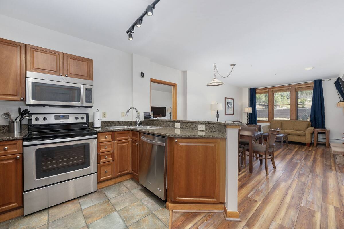 A modern kitchen with stainless steel appliances, wooden cabinets, and a dining area with a wooden table and chairs.