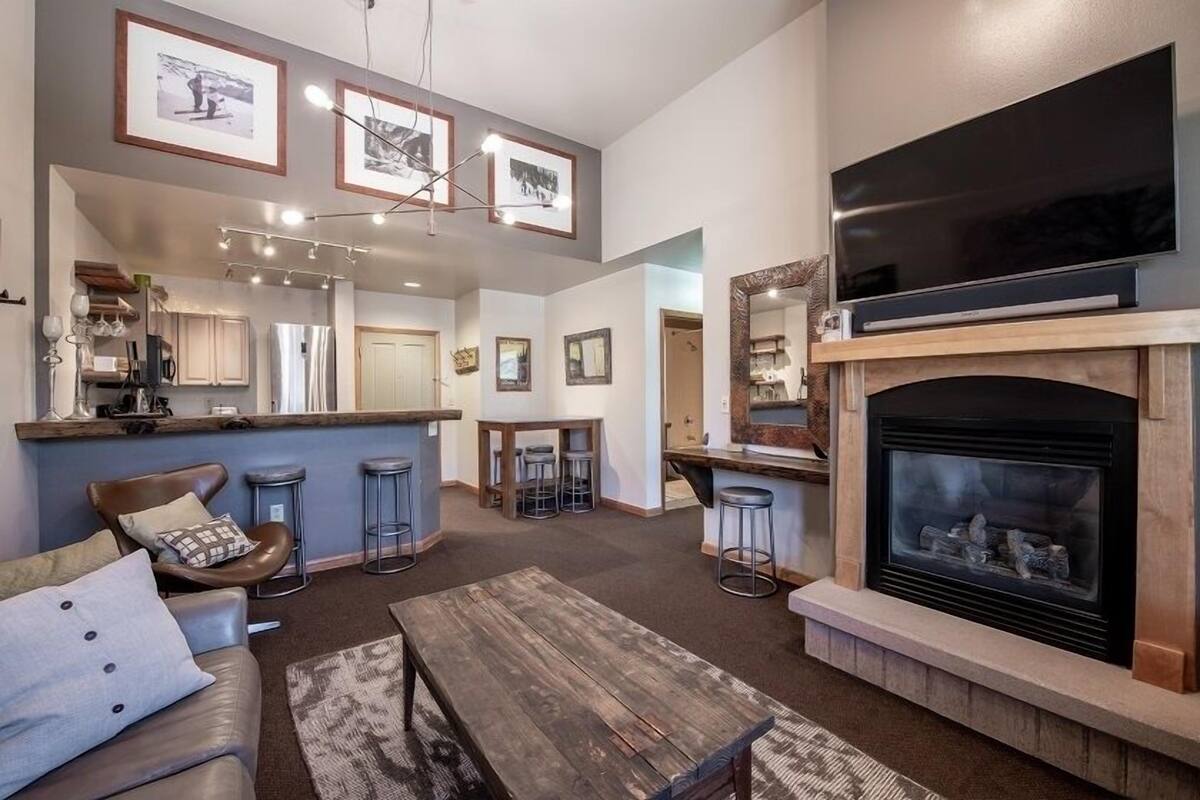 A spacious living room with a fireplace, a large TV, and a bar area.