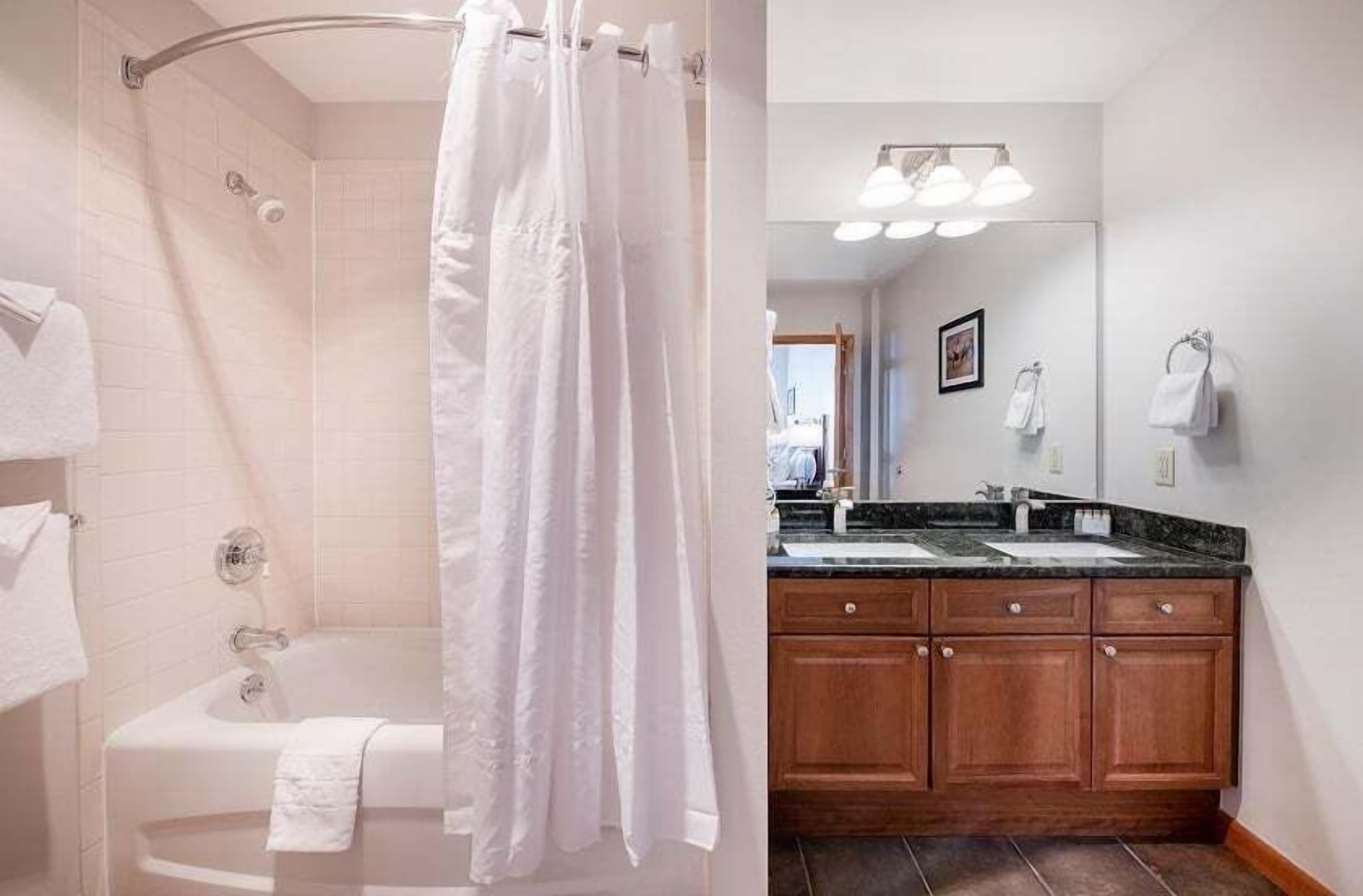 A bathroom with a bathtub, a shower, and a vanity with a sink and mirror.