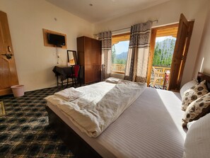 A bedroom with a bed, a desk, a chair, and a window with a view of mountains.