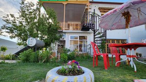A building with a balcony, a water tank, and a tire planter with flowers. - Yanglha Guest House (Leh)