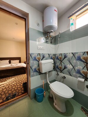 A compact hotel room with a bed, a toilet, and a shower.