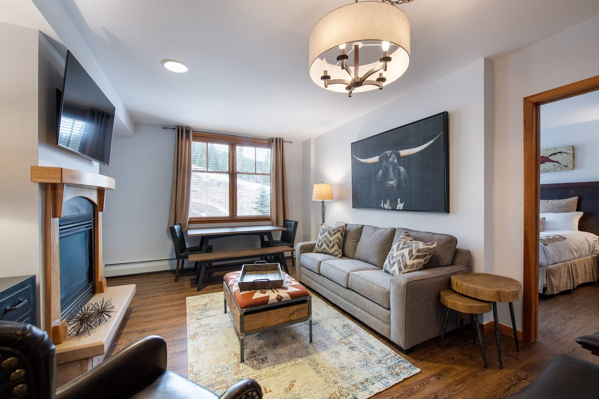 Un salon moderne avec une cheminée, un canapé, une table basse et un téléviseur fixé au mur.