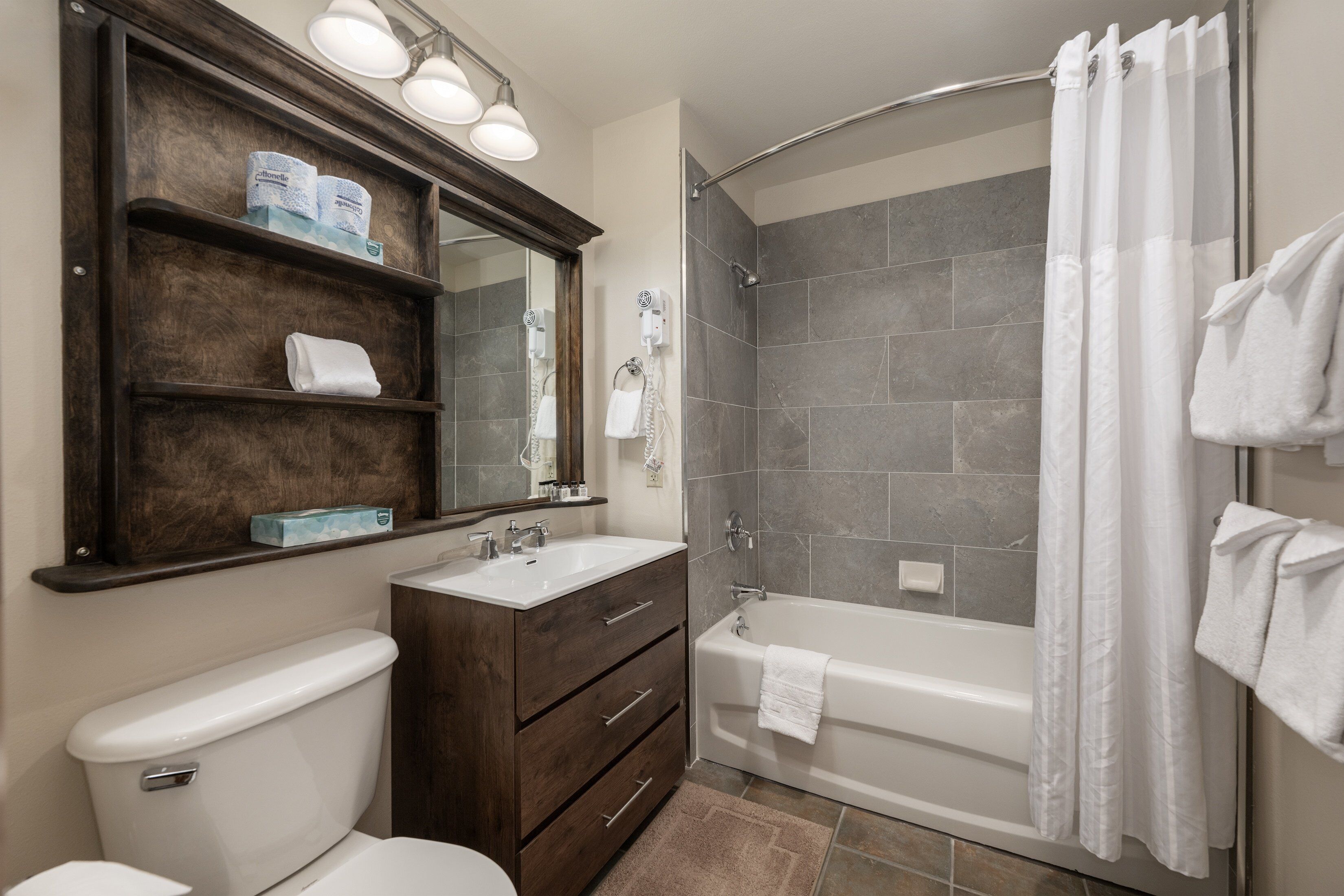 A bathroom with a toilet, vanity with drawers, a mirror, a shower with a glass door, and a bathtub.