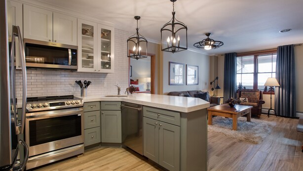 A modern kitchen with stainless steel appliances, a large island, and pendant lighting.