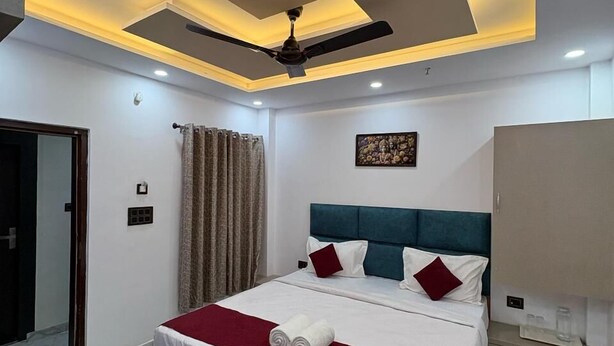A modern hotel room with a neatly made bed, a ceiling fan, and a large wardrobe. - Yatri Nivas By Sarvjeet Foundation (Varanasi)