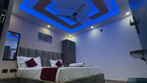 A modern bedroom with a bed, a ceiling fan, recessed lighting, a framed picture, and a wardrobe. - Yatri Nivas By Sarvjeet Foundation (Varanasi)