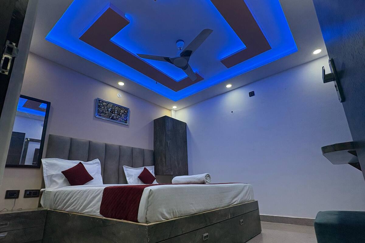 Une chambre à coucher moderne avec un lit, un ventilateur de plafond, des spots encastrés, un tableau encadré et une armoire.