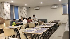 Une salle de conférence aux murs de marbre, dotée de systèmes de climatisation et de tables accompagnées de chaises.