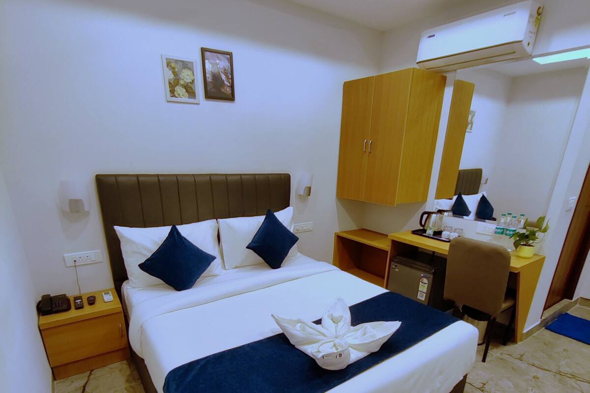Une chambre d’hôtel avec un grand lit, un bureau, une chaise, une armoire et un miroir.