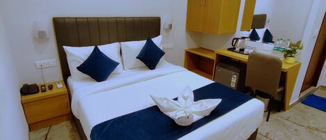 A hotel room with a large bed, a desk, a chair, a wardrobe, and a mirror.