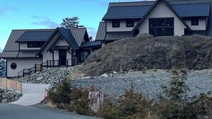 Una hilera de edificios modernos de varios pisos con techo inclinado, ubicados en un terreno rocoso bajo un cielo despejado.