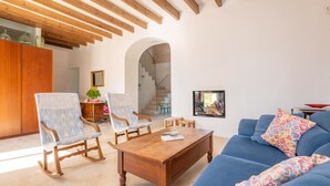 A living room with a blue sofa, wooden rocking chairs, a wooden coffee table, and a staircase in the background. - CA SES FALIES - Rustic villa with private pool and free wifi (Felanitx)