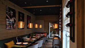 Un restaurant aux murs en bois, doté de luminaires suspendus et d’un long comptoir avec des places assises.