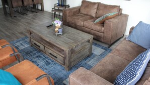 Un salon avec un canapé marron, une table basse en bois et un coussin bleu à motifs.