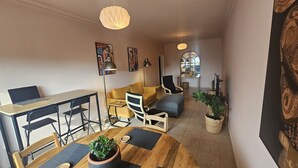 A modern living room with a wooden dining table, a yellow sofa, and a laptop on a desk. - STAY Velvet Apartment (Limassol)