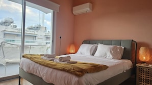 A hotel room with a bed, a balcony view, and an air conditioning unit. - STAY Velvet Apartment (Limassol)