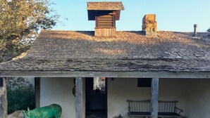 A rustic building with a sloped roof, a wooden bench, and a green sculpture. - Soul & Sea #1 – East Beach Guesthouse (Santa Barbara)