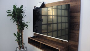 A flat-screen TV mounted on a wooden wall with a shelf below. - Encantador apartamento nuevo de 1 dormitorio WiFi aire acondicionado Cartagena (Cartagena de Indias)