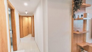 A hallway with wooden doors and a modern TV shelf. - Royal Home Deluxe Apartments, Beach View, 5min to Corniche (Abu Dhabi)