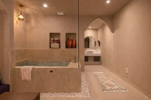 Un baño moderno con una bañera independiente, un tocador con espejo y un tapete decorativo.