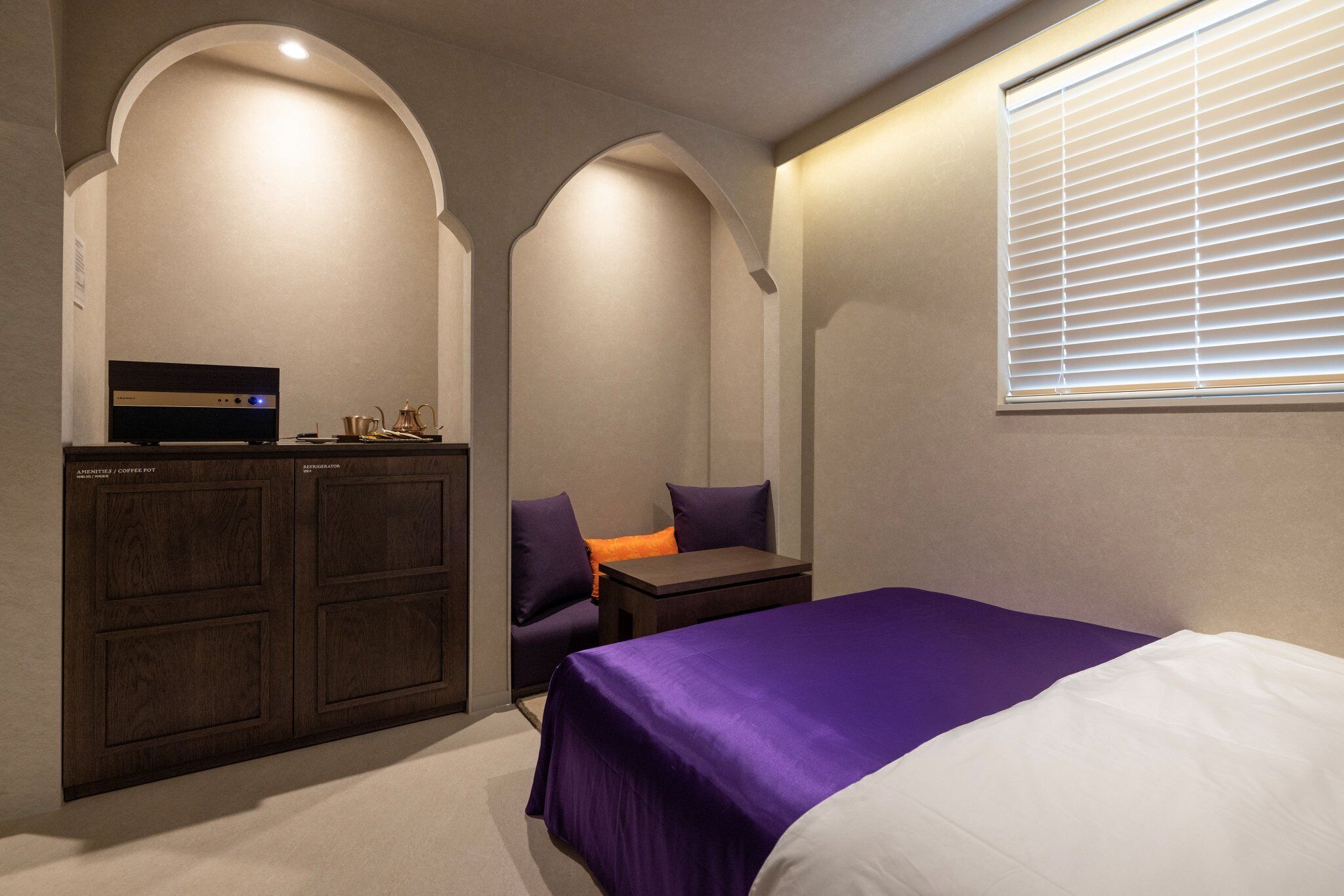 A bedroom with a bed, a desk, and a coffee maker.