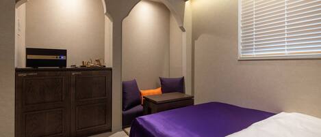 A bedroom with a bed, a desk, and a coffee maker.