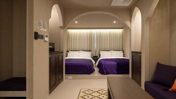A hotel room with two beds, a desk, and a sofa.
