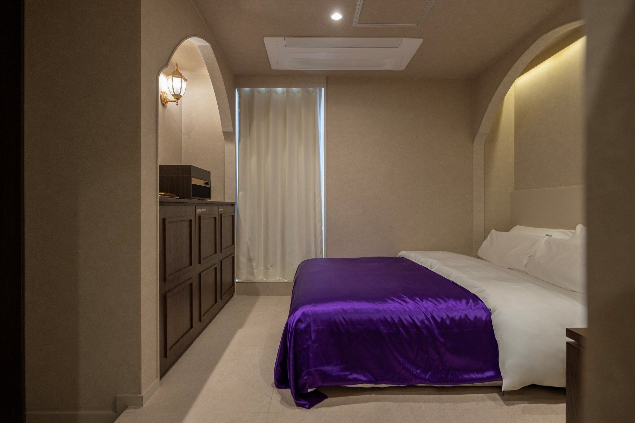 Un dormitorio con una cama, un armario y una ventana con cortinas.