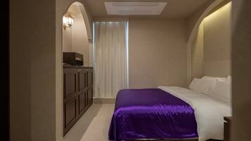 Un dormitorio con una cama, un armario y una ventana con cortinas.
