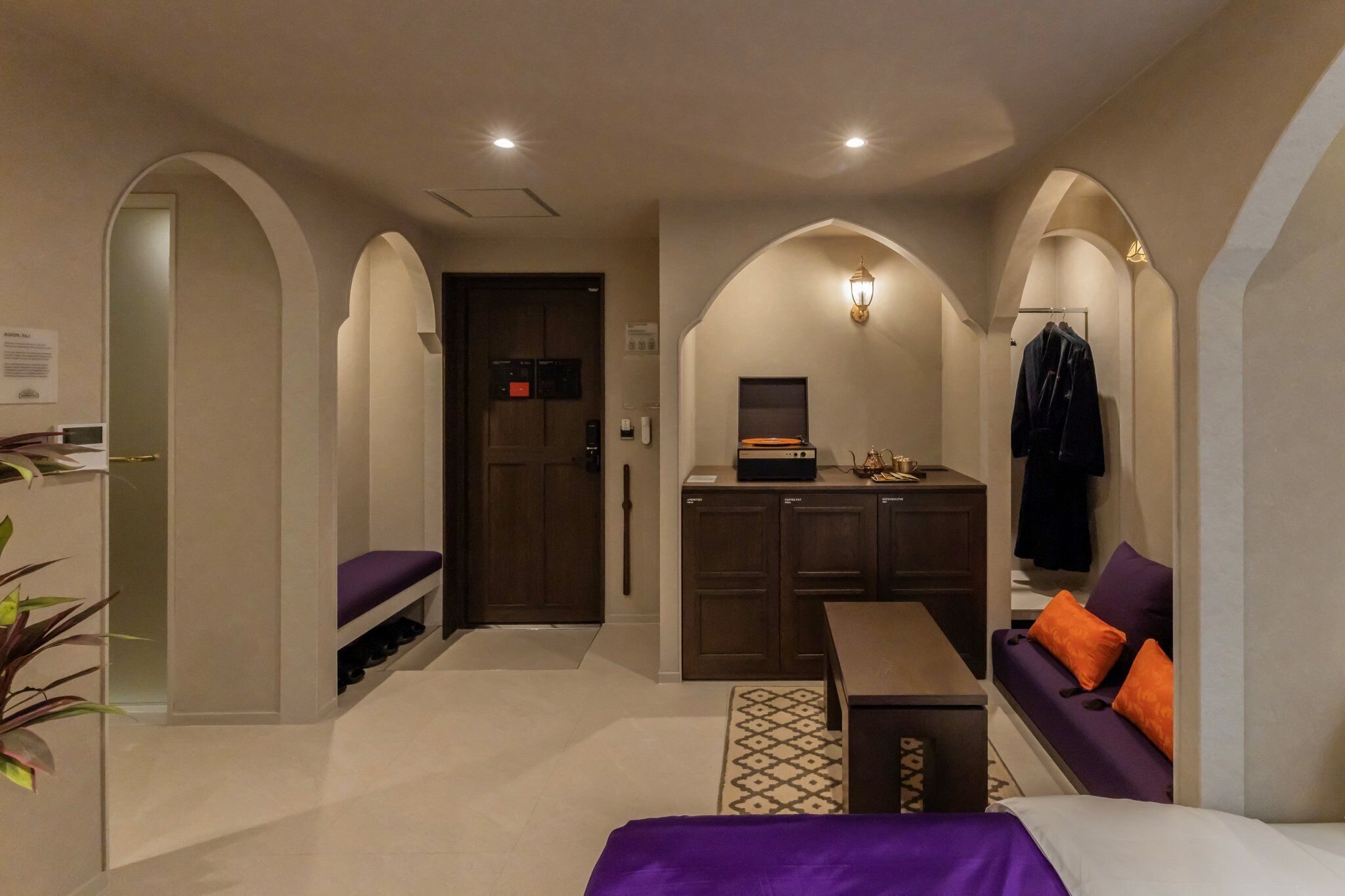 A hotel room with a bed, a desk, a chair, a sofa, and a small kitchenette.