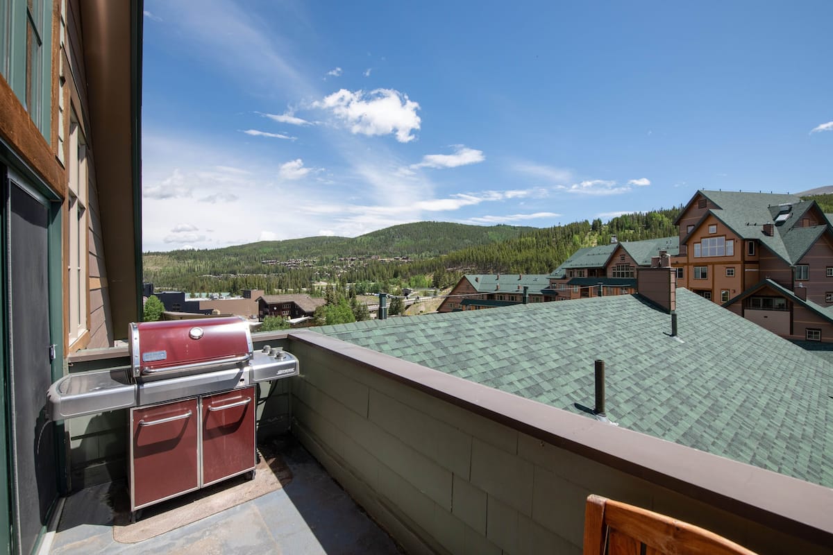 A balcony with a grill and a view of a town and mountains.