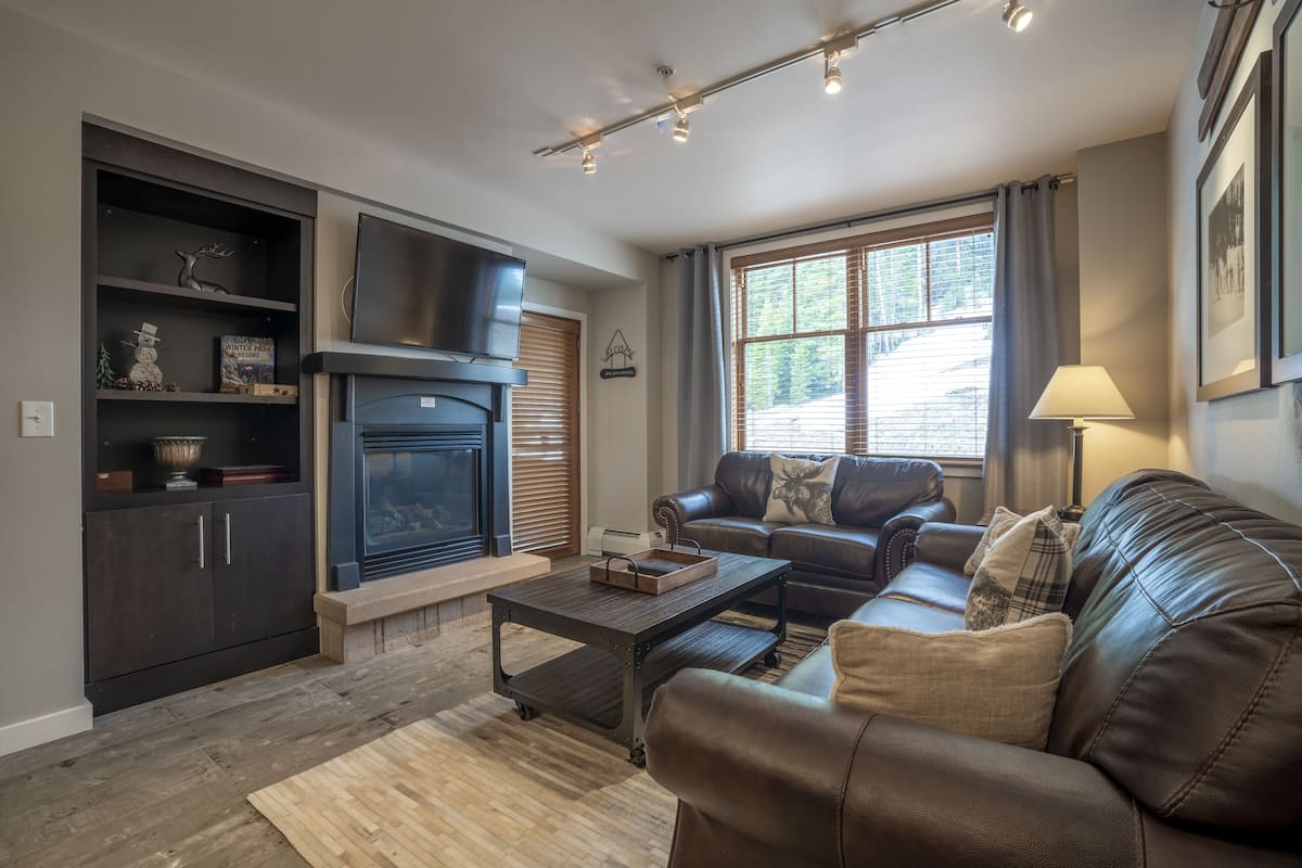 A living room with a fireplace, leather sofa, and a television.