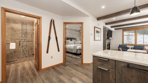 A modern kitchen with wooden cabinets, a marble countertop, and a stone fireplace. - Two Bedroom Condos at Zephyr Mountain Lodge - Winter Park CO (Winter Park)