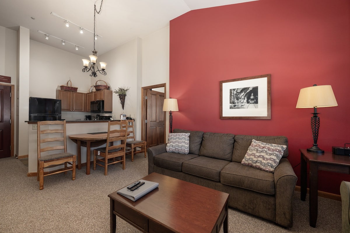 A living room with a sofa, coffee table, and a dining area with chairs and a table.