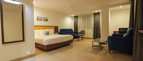 A hotel room with a bed, a desk, a chair, and a sofa.