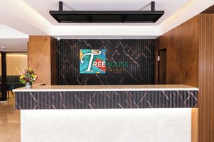 Un mostrador de recepción con un logotipo y la frase "TREE HOUSE PRIDE" en la pared de fondo.