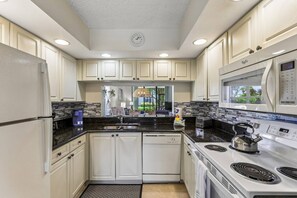 A modern kitchen with white cabinetry, a built-in microwave, a stove, and a sink.