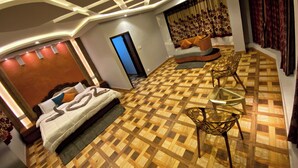 A modern hotel room with a large bed, a glass table, and a patterned floor. - Magic Mist Resort A Boutique Resort (Ooty)