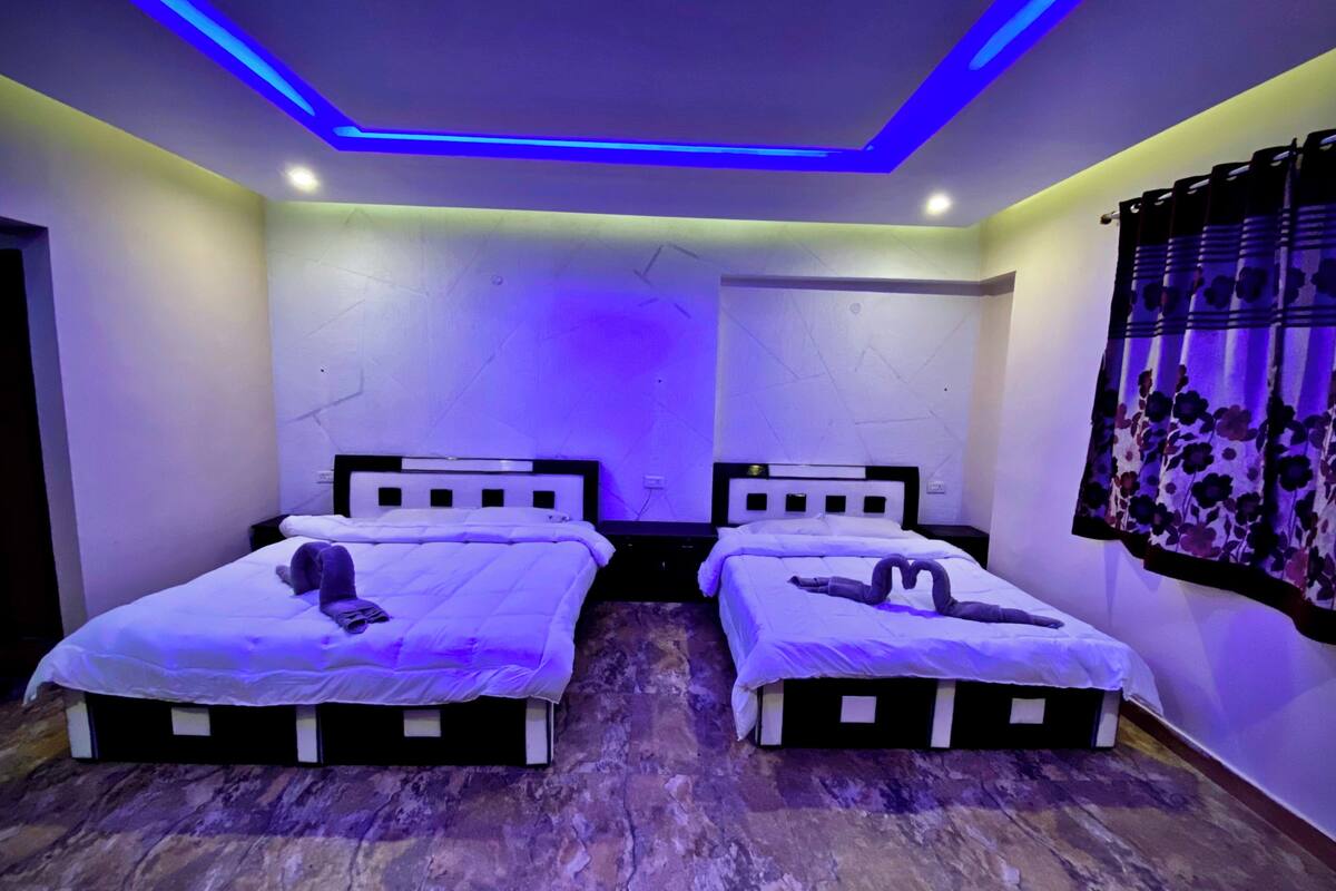 Een kamer met twee bedden, een plafondlamp en een raam met gordijnen.