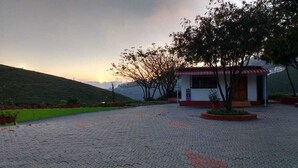 A small building with a red roof, surrounded by a paved area with potted plants. - Magic Mist Resort A Boutique Resort (Ooty)