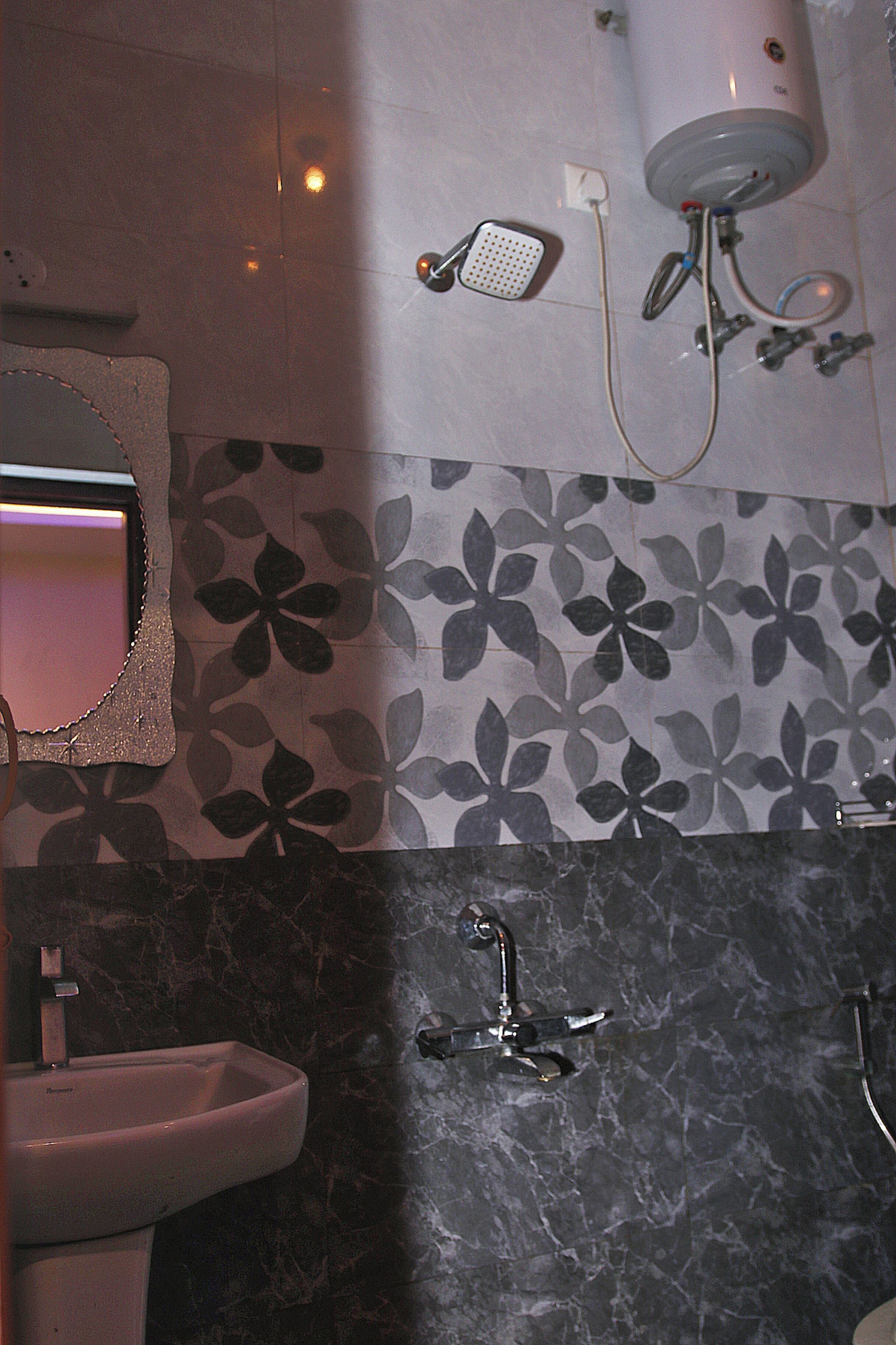 A bathroom with a white sink, a mirror, a shower head, and a water heater.