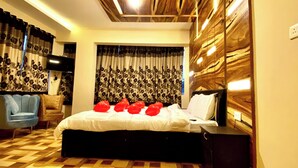 A modern bedroom with a wooden ceiling, a patterned curtain, a bed with red pillows, and a blue armchair. - Magic Mist Resort A Boutique Resort (Ooty)