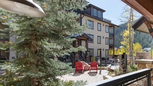 A balcony with a view of a building, a Christmas tree, and outdoor seating. - Winter Park Resort Lodging - Convenient Condos (Winter Park)