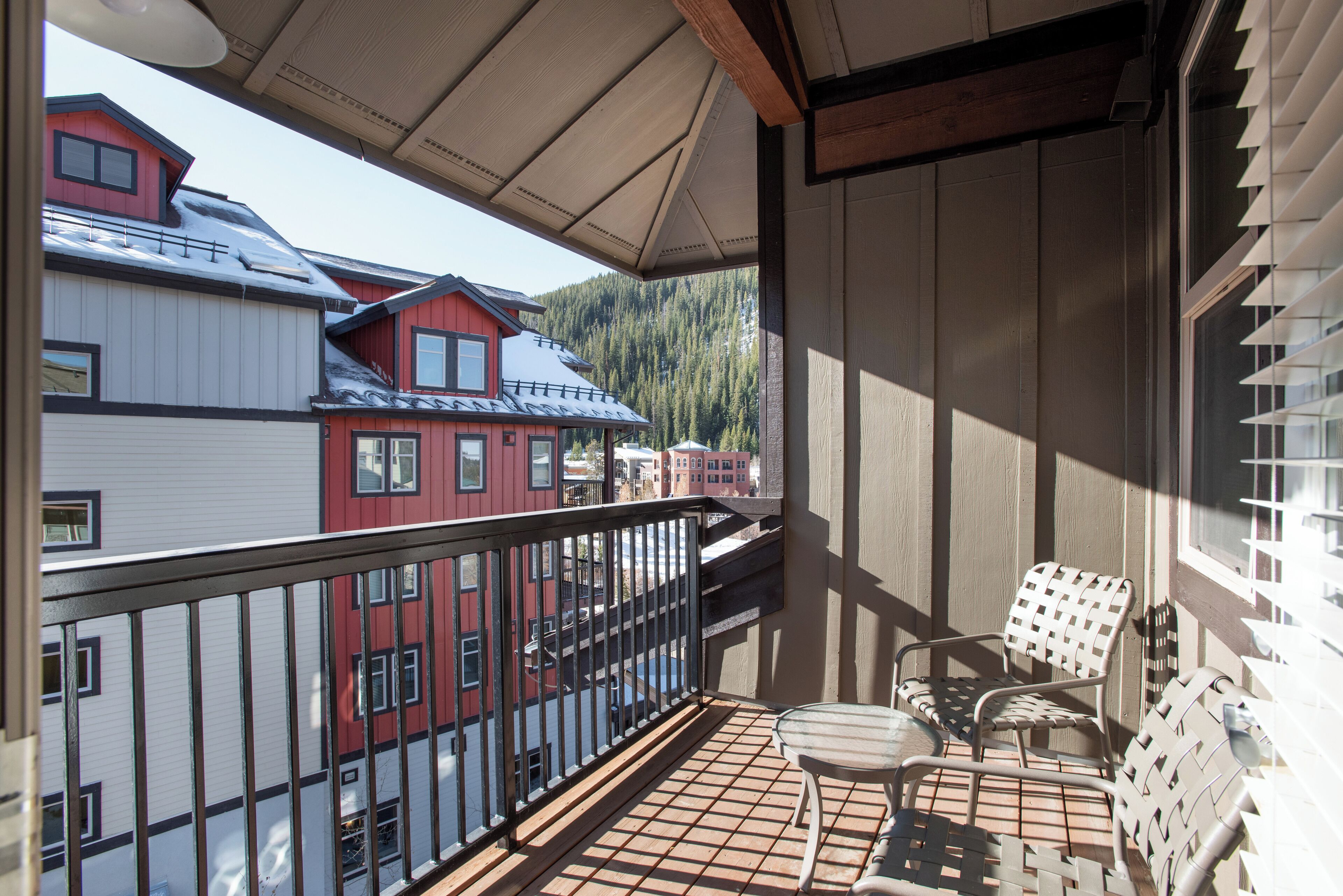 A balcony with a view of neighboring buildings and a mountain.